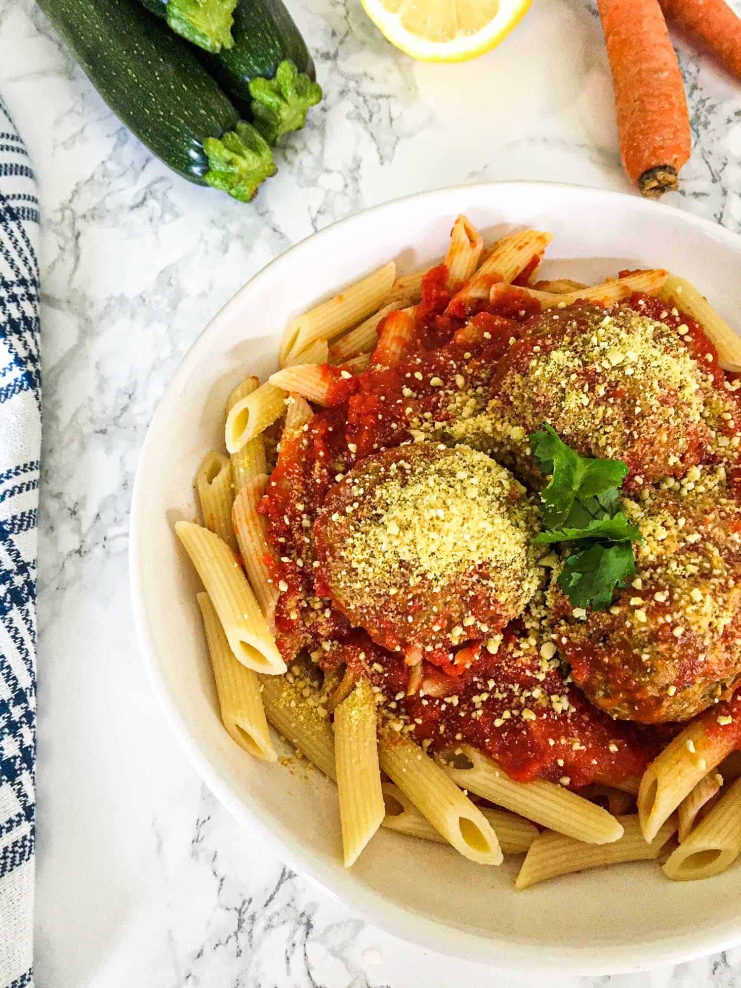 pasta and meatballs in plate with basil garnish