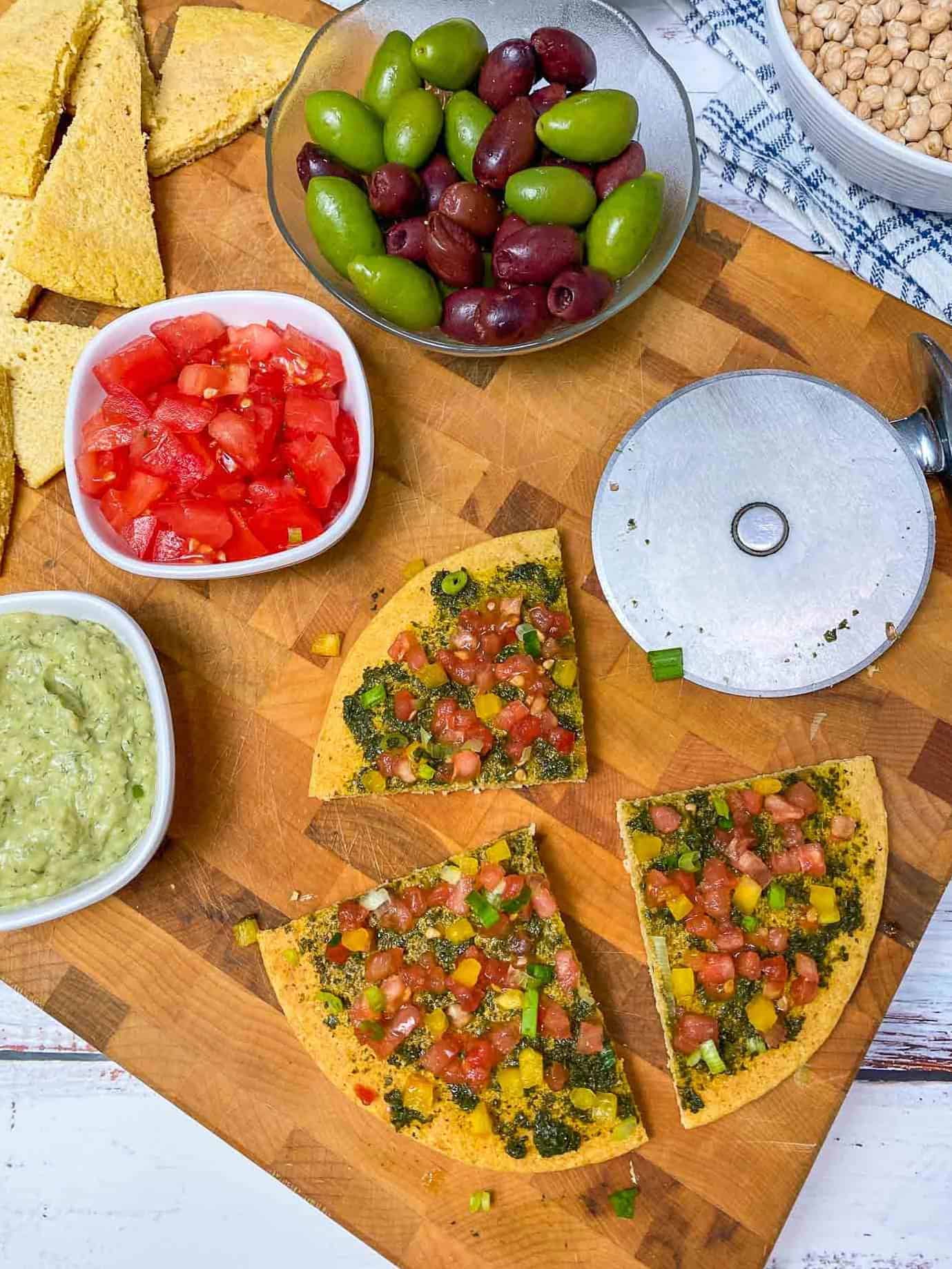 socca pizza sliced into triangular pieces on cutting board