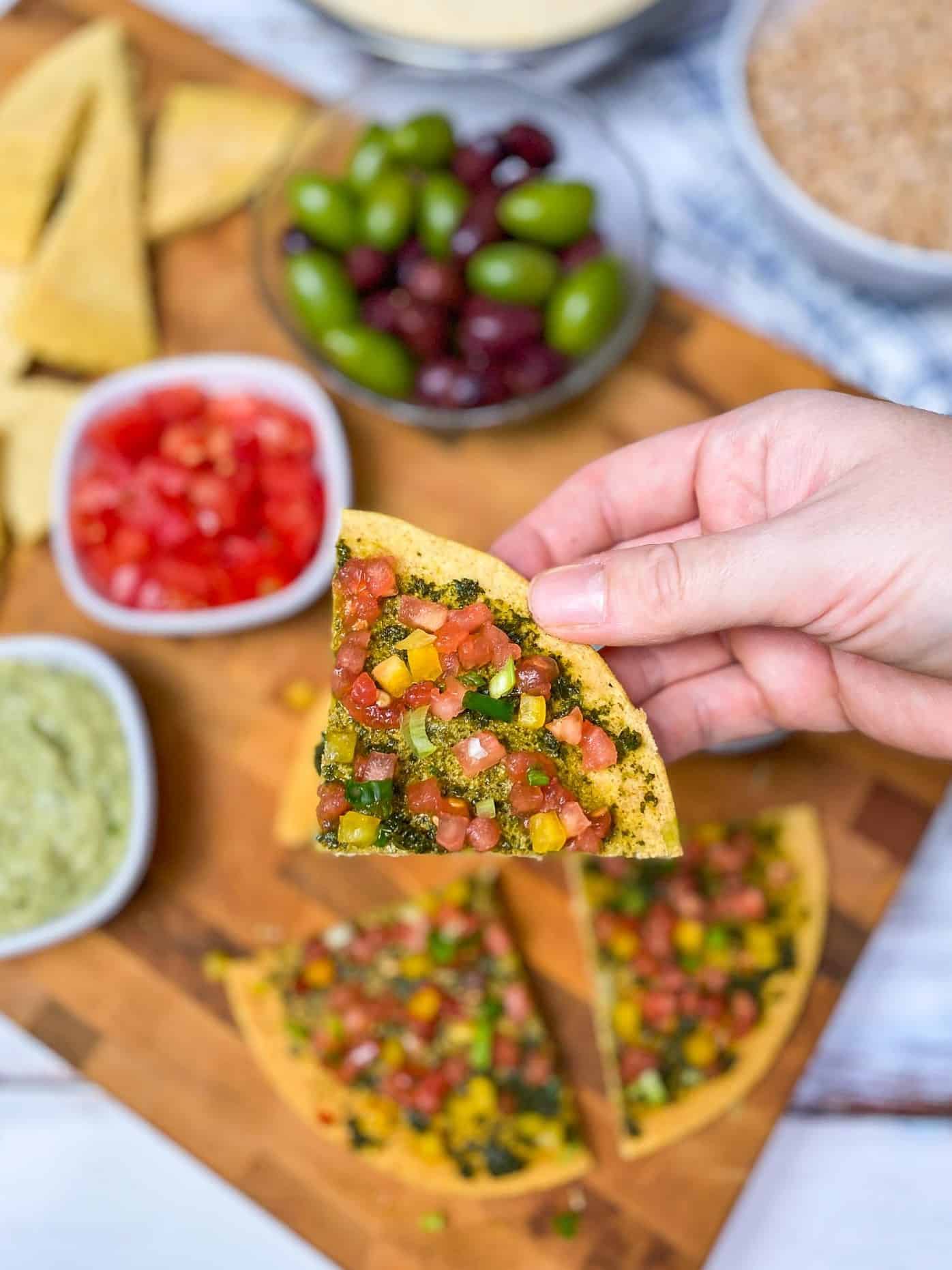 hand holding up slice of socca pizza