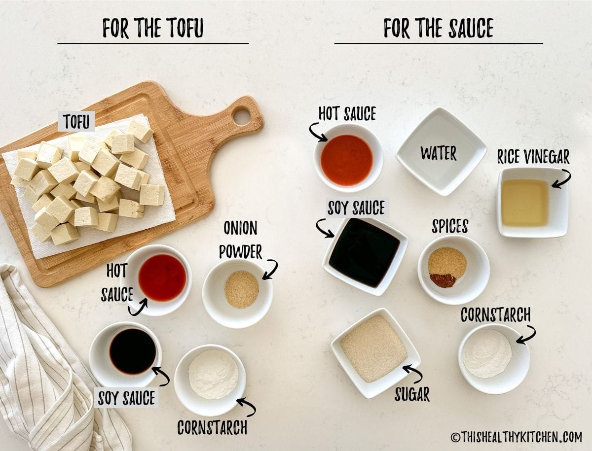 Cubed tofu and prep bowls of spices and sauces on kitchen countertop.