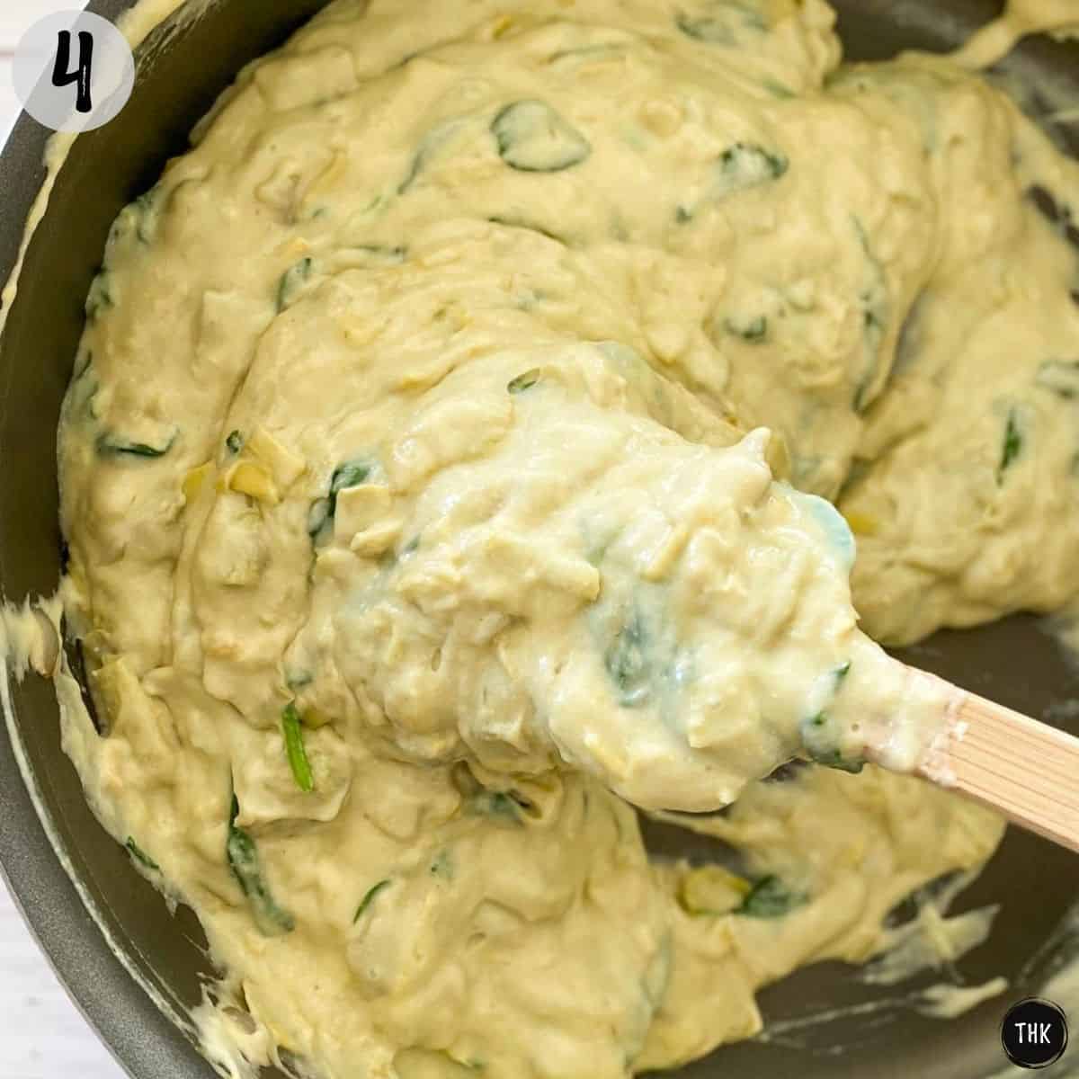 Spatula stirring creamy mixture in nonstick skillet.
