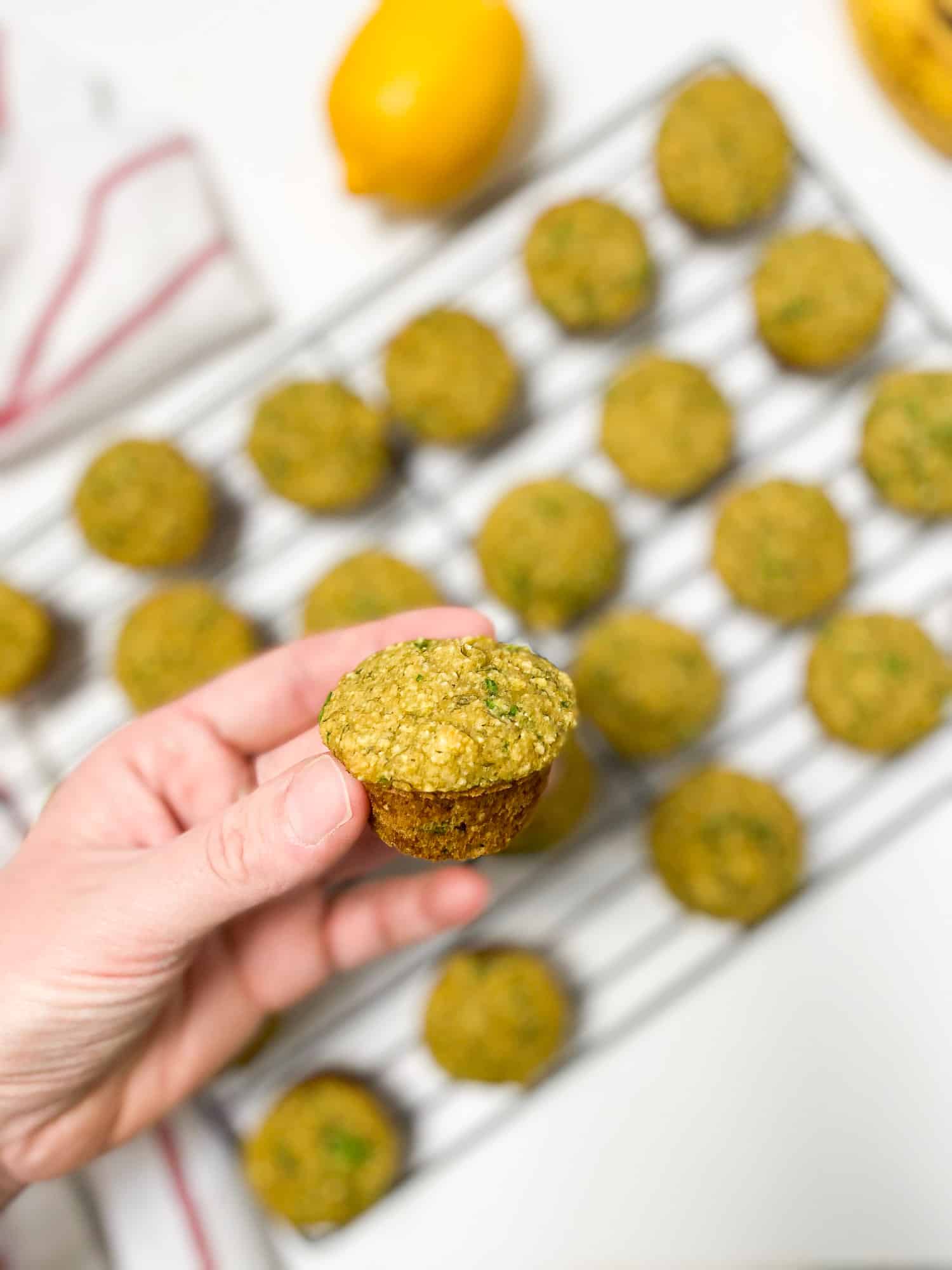 hand holding up a spinach banana muffin with more muffins below