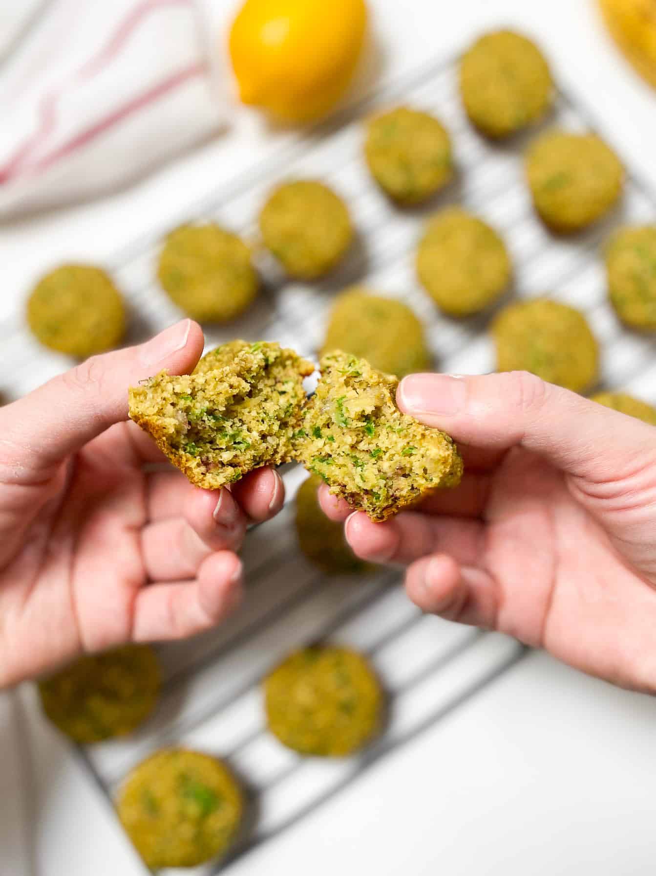 hand breaking mini muffin in half to expose green spinach ribbons inside