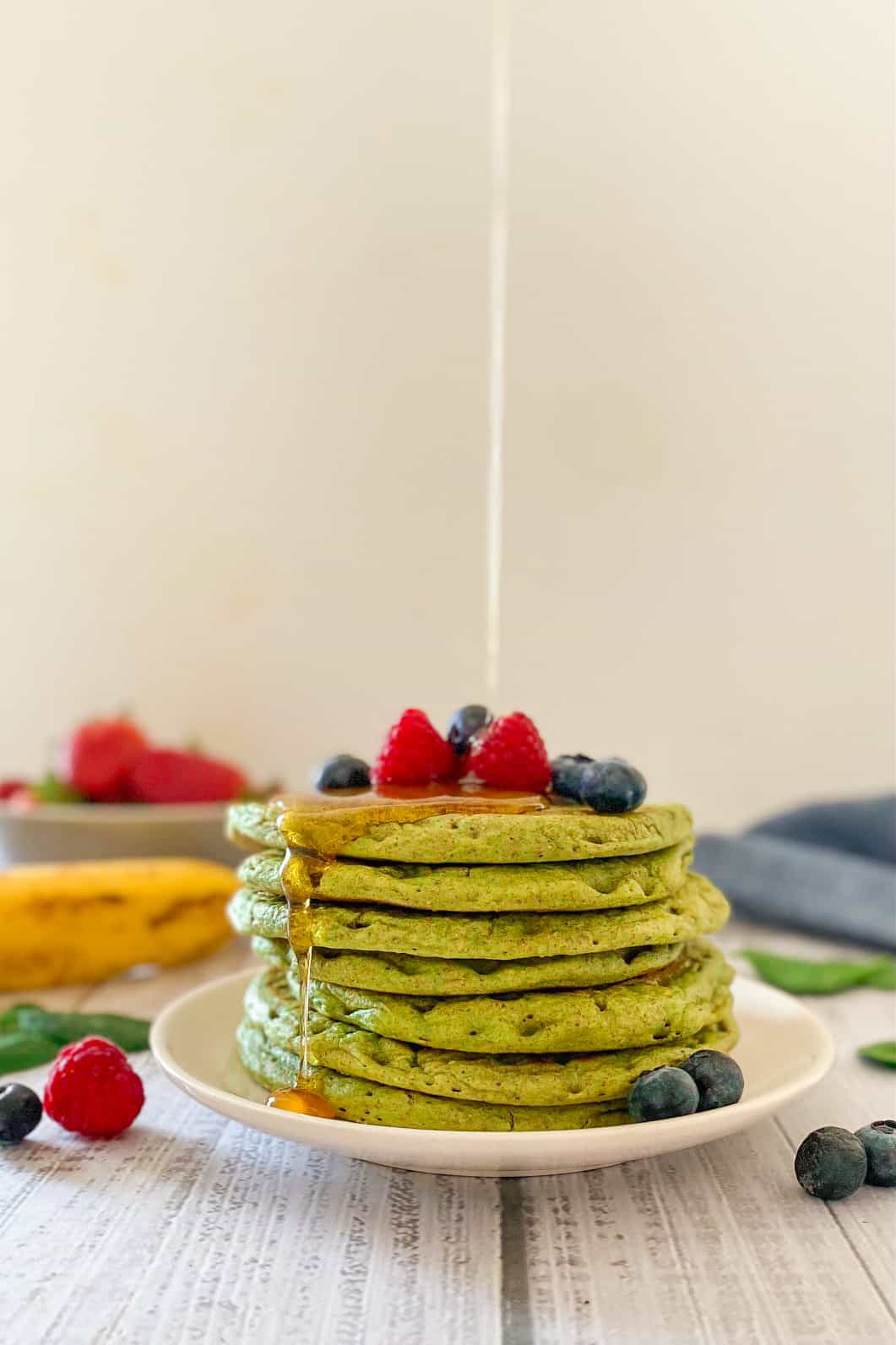 Syrup pouring over stack of green pancakes.