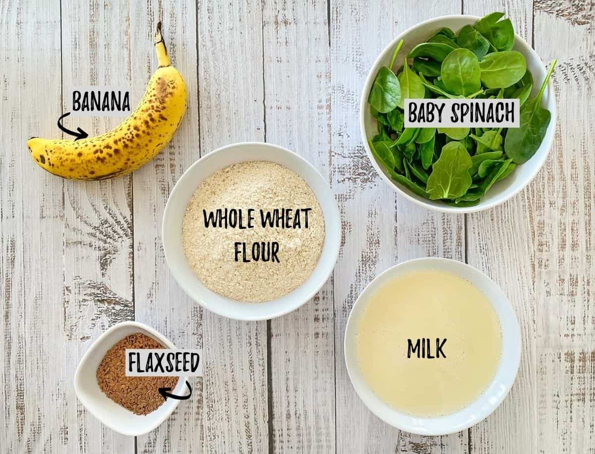 Bowls of spinach, flour, milk, flaxseed and a banana scattered on deck.