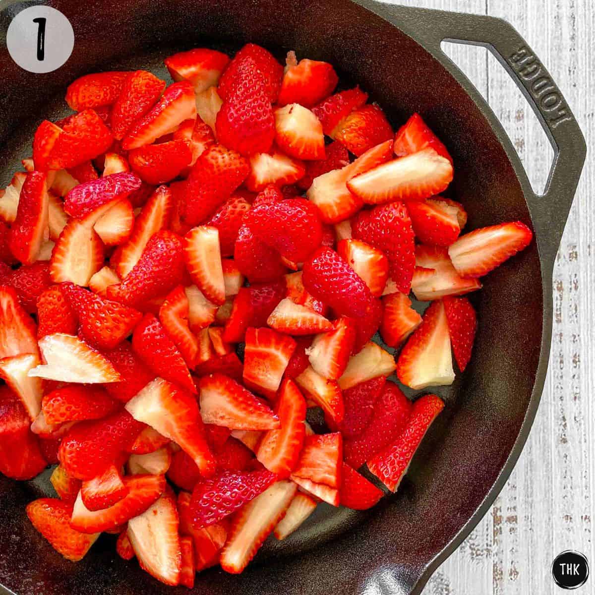 Quartered strawberries inside cast iron pan.