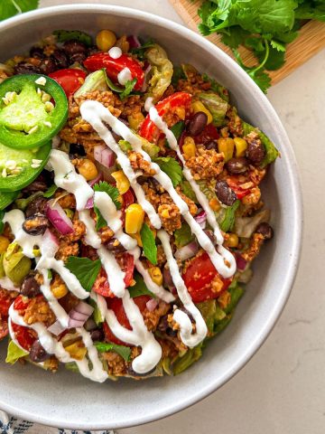 Vegan taco salad with veggies, black beans, and jalapenos on top.