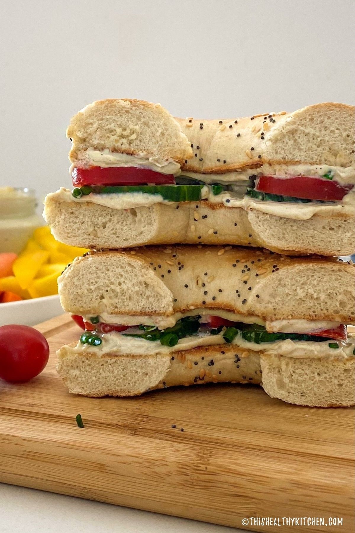 Bagel cut in half with cream cheese, cucumber and tomato slices inside.