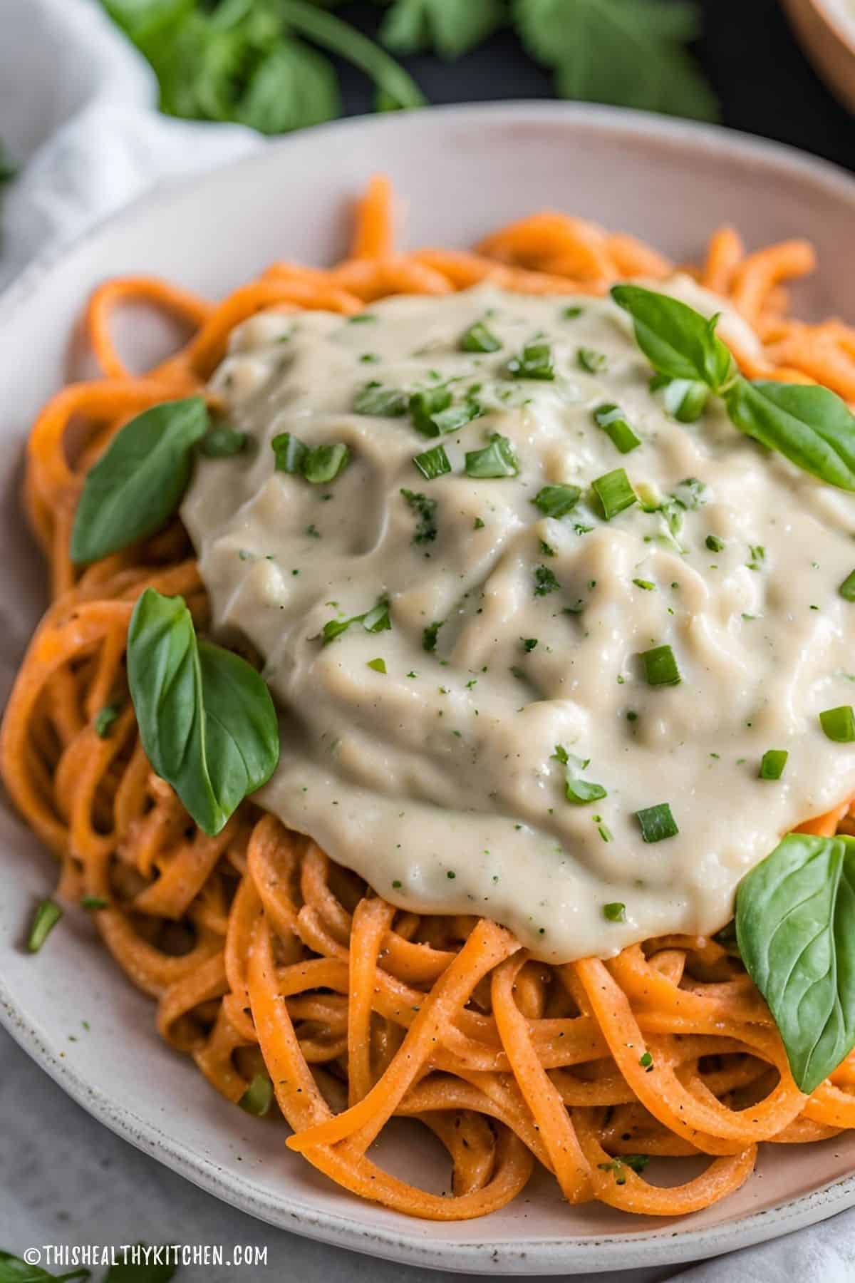 Sweet potato noodles with vegan alfredo sauce and fresh herbs on top.