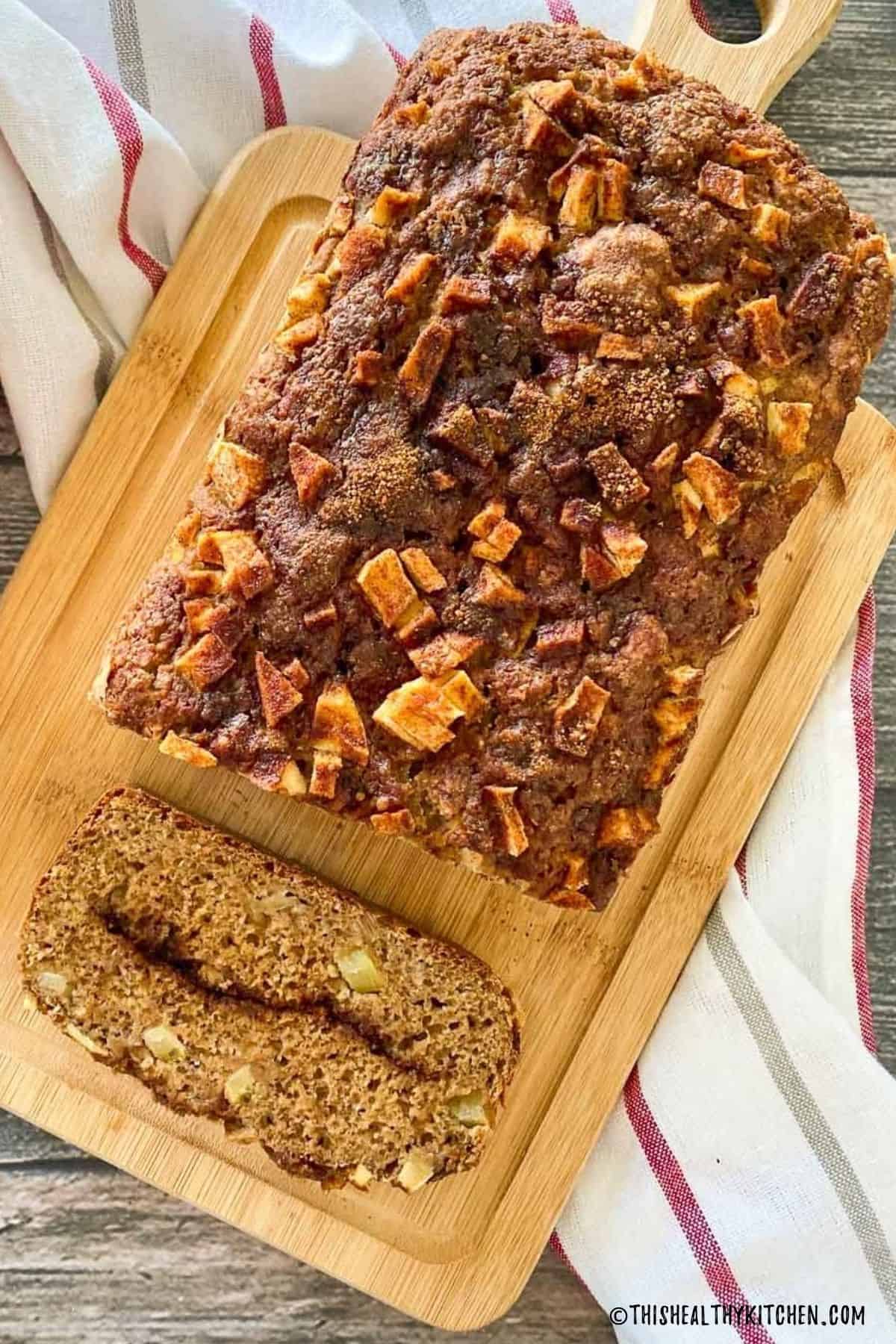 Apple bread on cutting board with one slice cut and resting on its side.