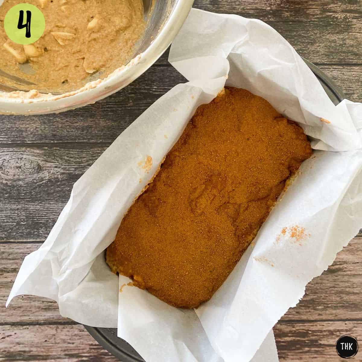 Apple bread batter inside loaf pan with cinnamon and brown sugar on top.