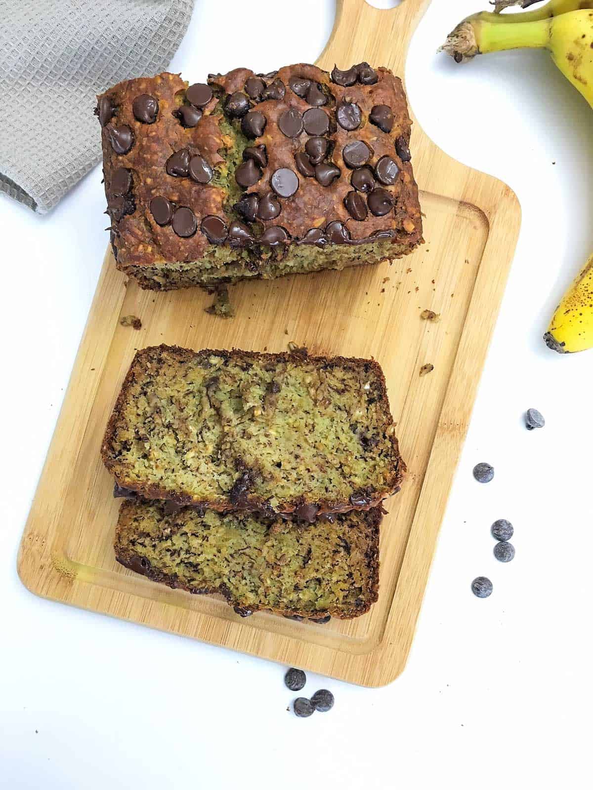 Overhead view of banana bread on cutting board with two slices laying on their sides.