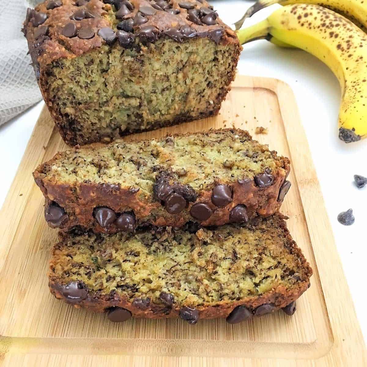 banana bread loaf on cutting board with two slices laying on their side.