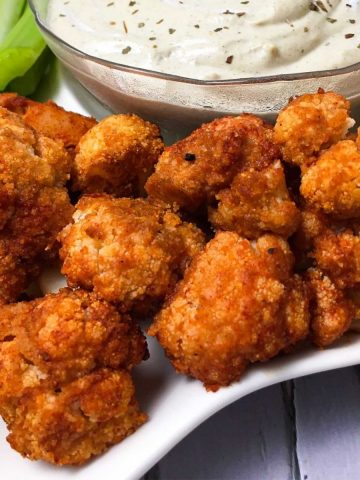 Tray of buffalo cauliflower bites with bowl of ranch dip in the middle.