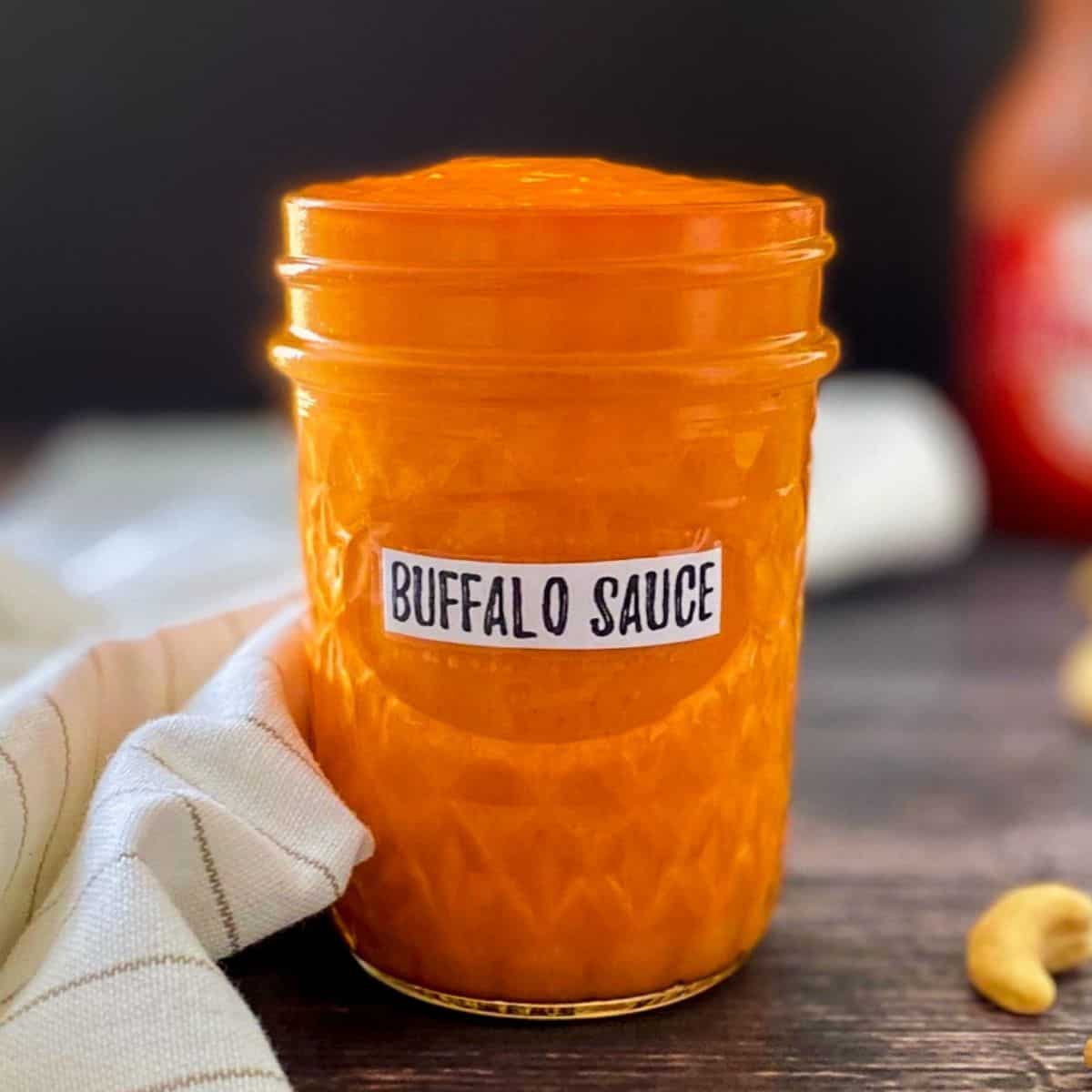 Glass jar with buffalo sauce inside.
