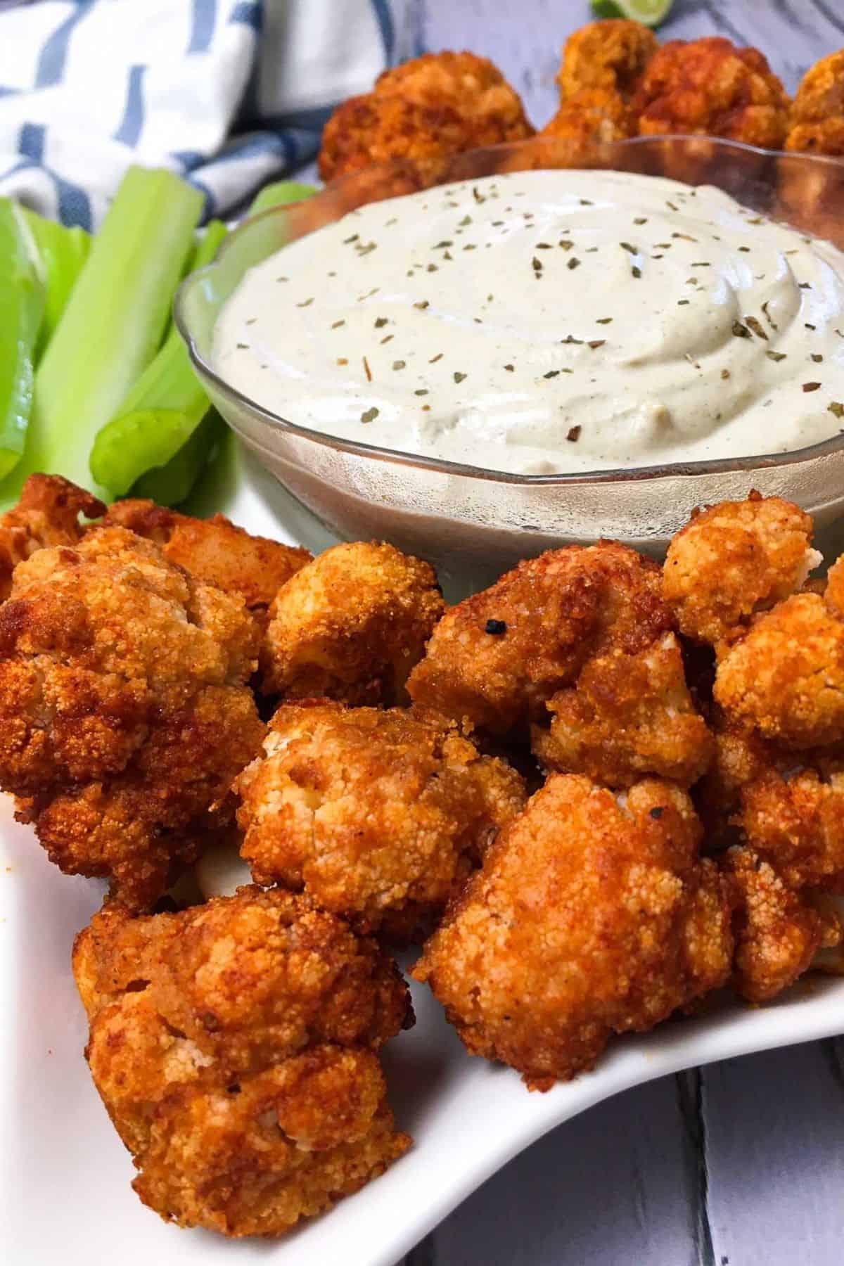 Tray of buffalo cauliflower bites with bowl of ranch dip in the middle.