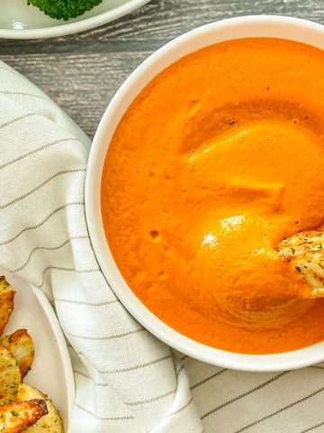 Potato wedge being dipped into vegan cheese sauce.