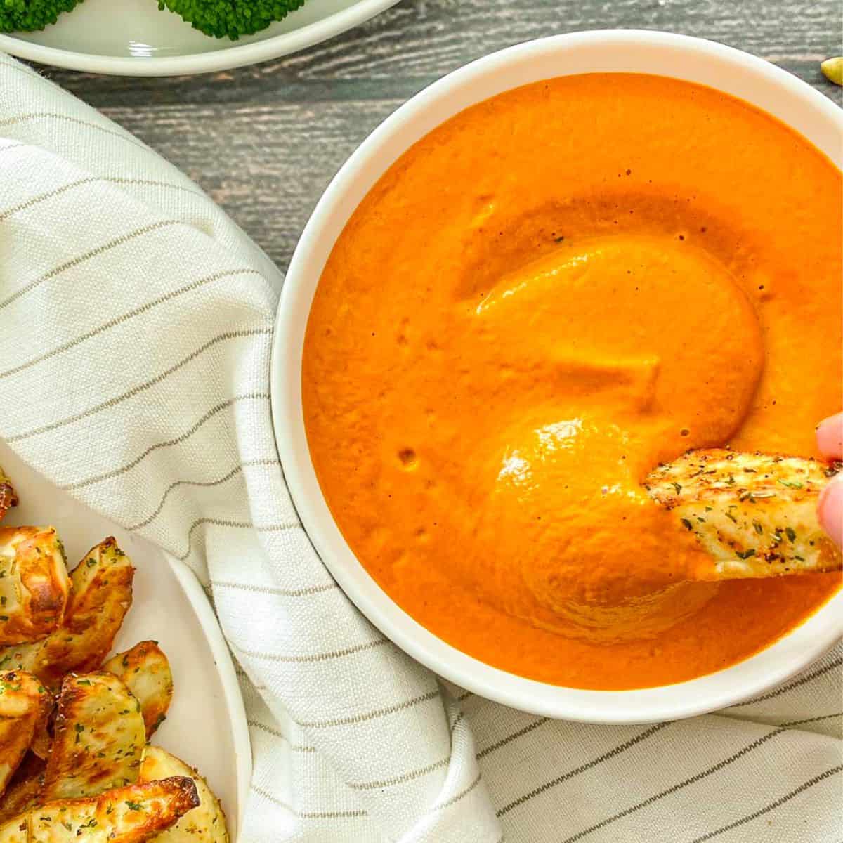 Potato wedge being dipped into vegan cheese sauce.
