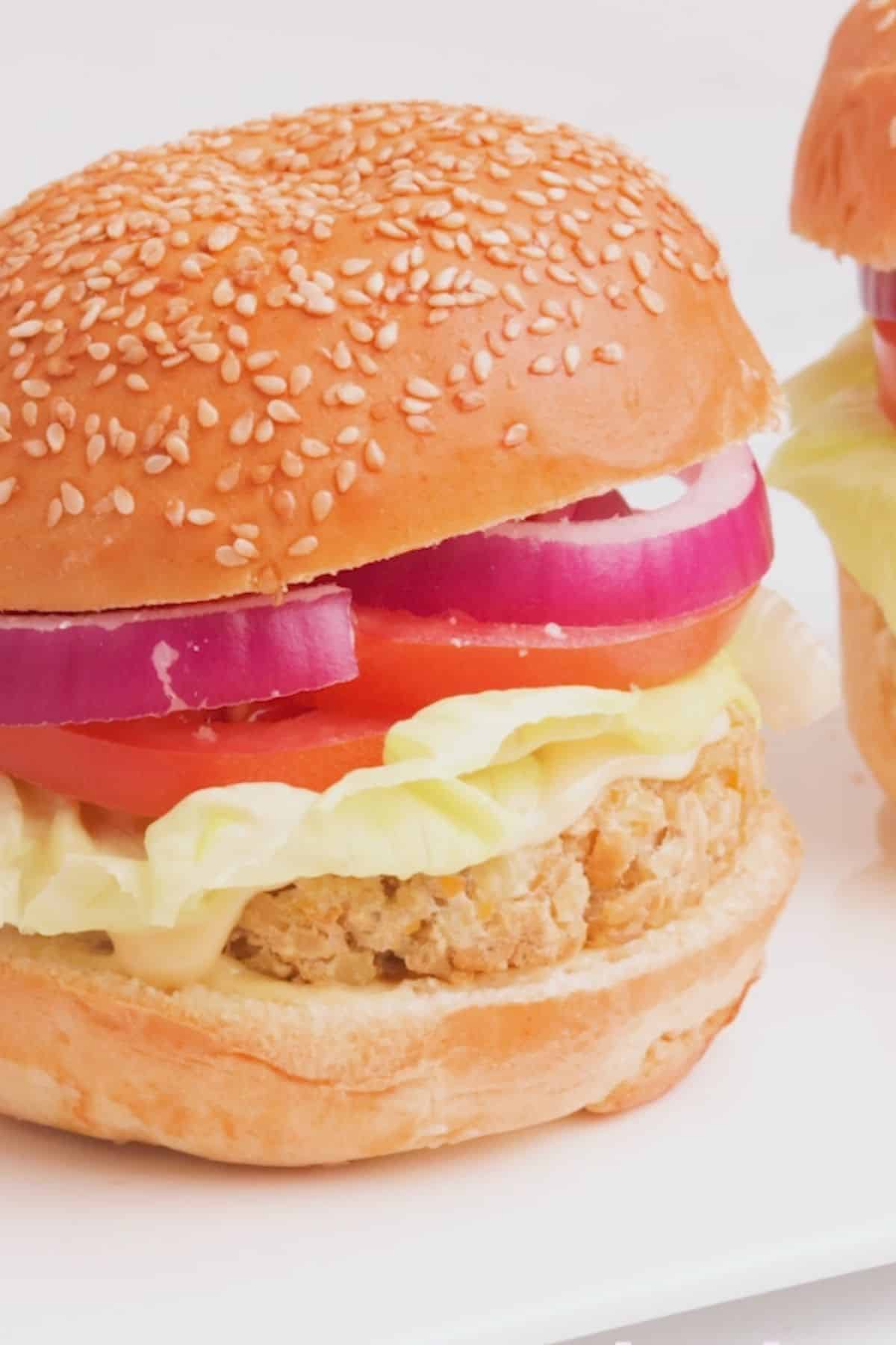 Vegan chicken burger in bun with onion, tomato, lettuce and mayo.