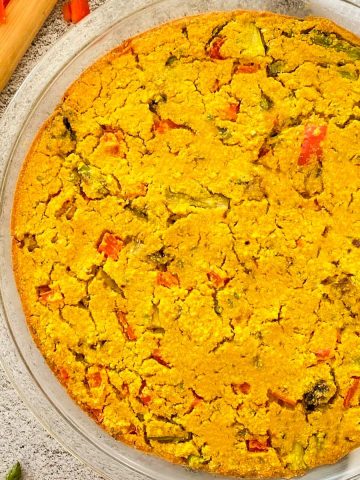 Vegan frittata in pie plate with asparagus and red peppers inside.