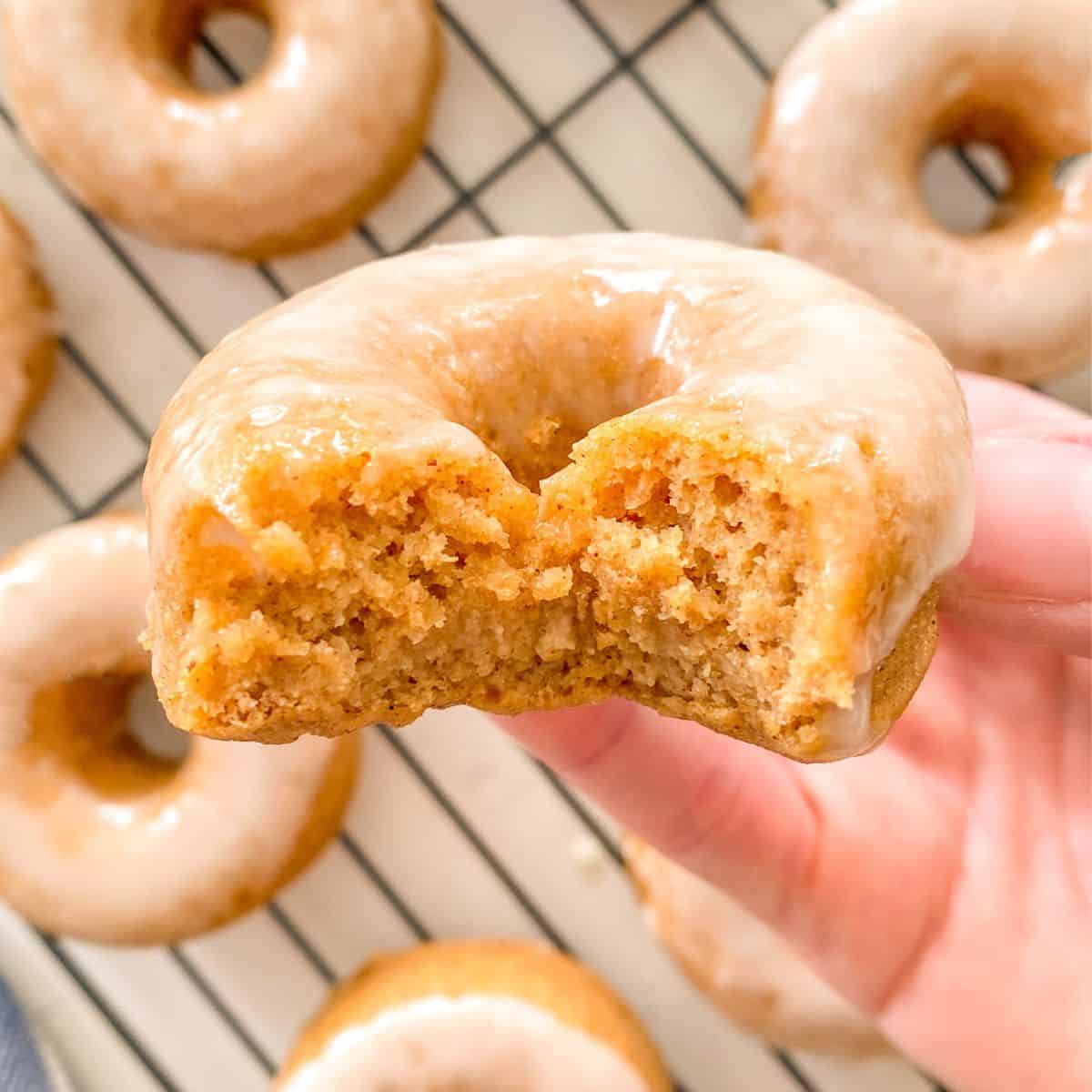 Hand holding up donut with bite taken from it.