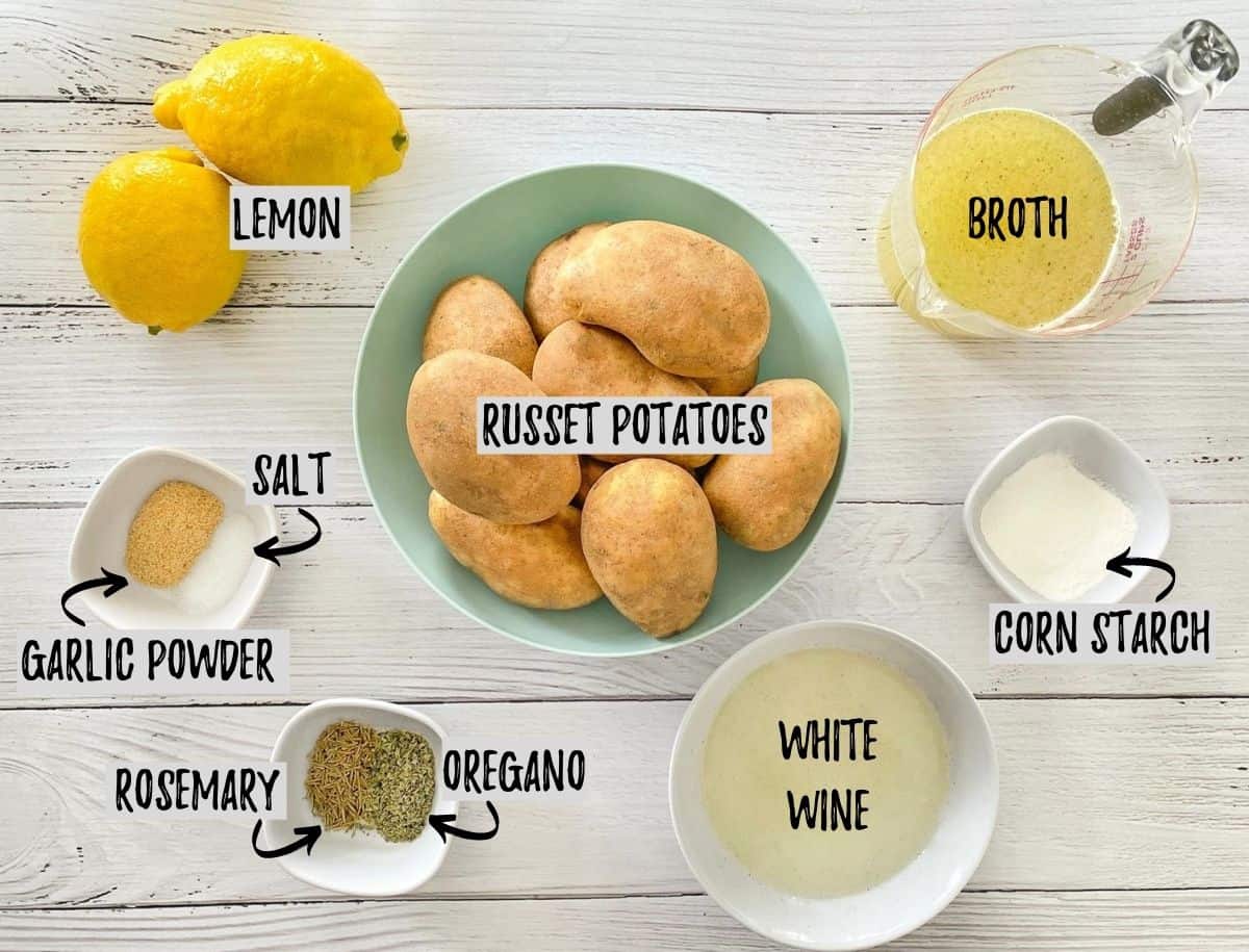 Bowls of potatoes, lemons, broth and seasoning on white deck. 