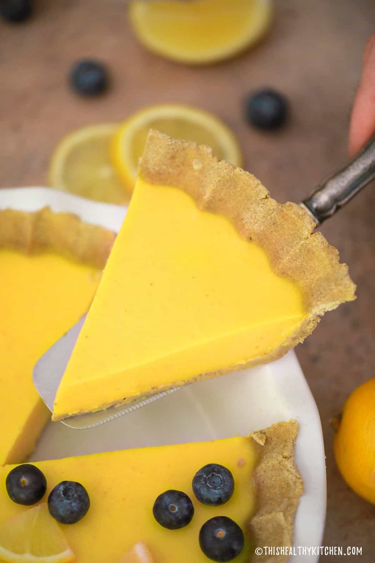 Pie server lifting slice of lemon pie from plate.