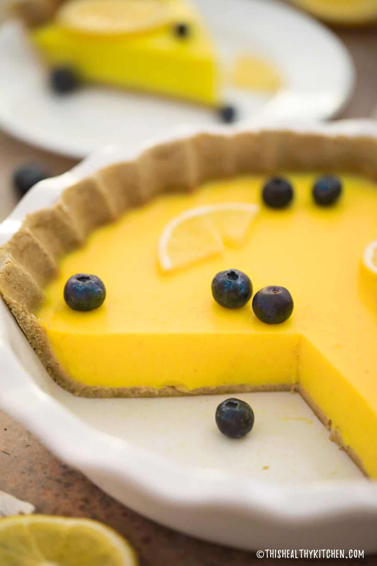 Lemon pie in white pie plate with slice removed.