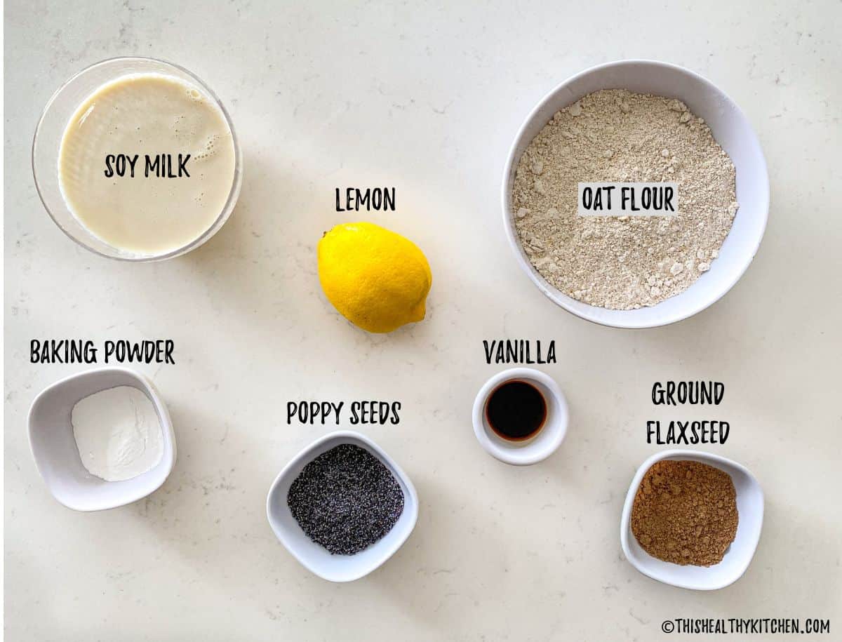Bowl of flour, milk, vanilla, poppy seeds, flaxseed, and baking powder on kitchen counter.