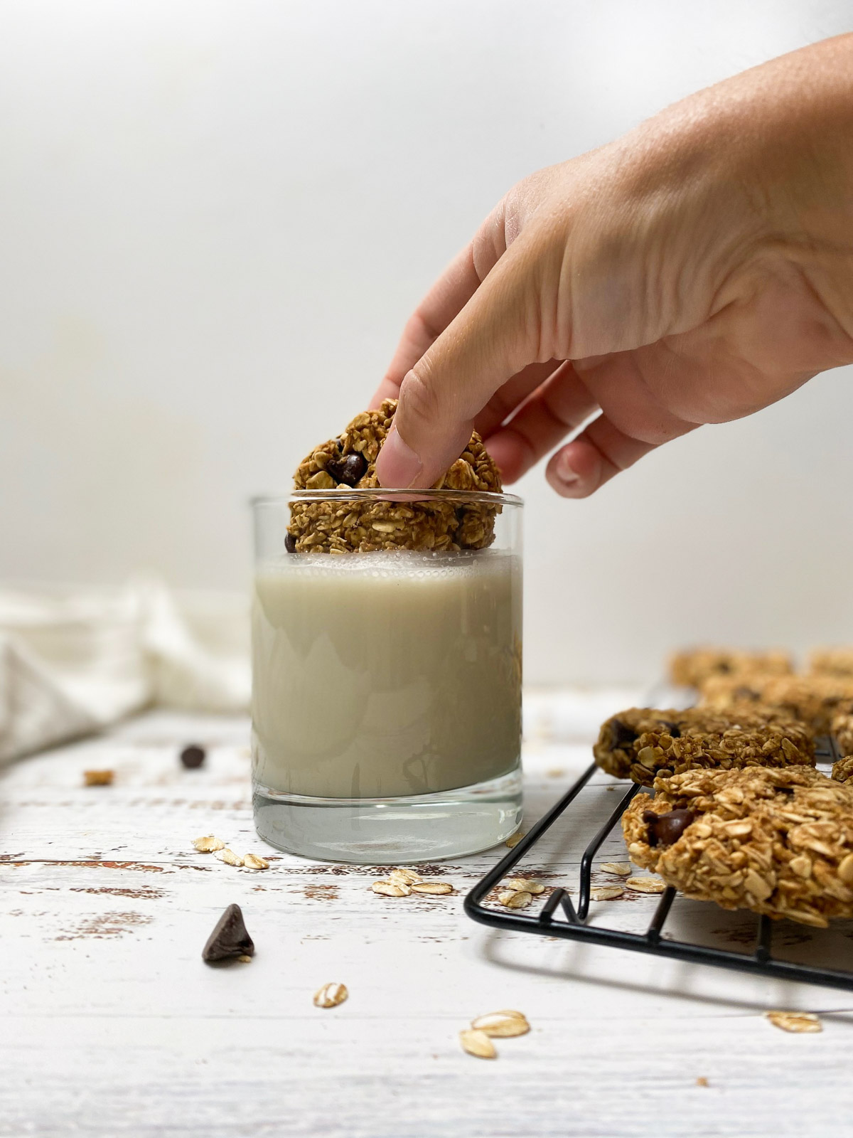 hand dunking cookie into glass of milk