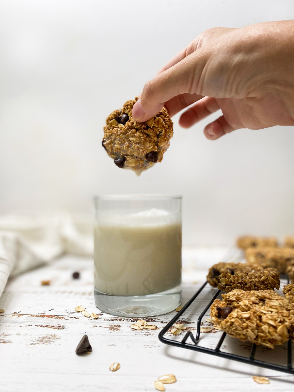 cookie dipped in glass of milk with drop of milk dripping down