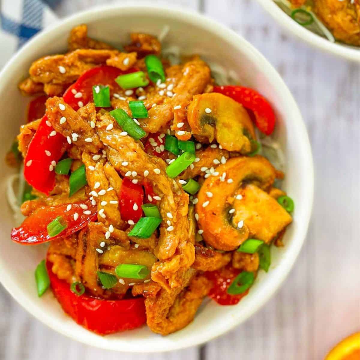 Soy curls with peppers and mushrooms in a white bowl.