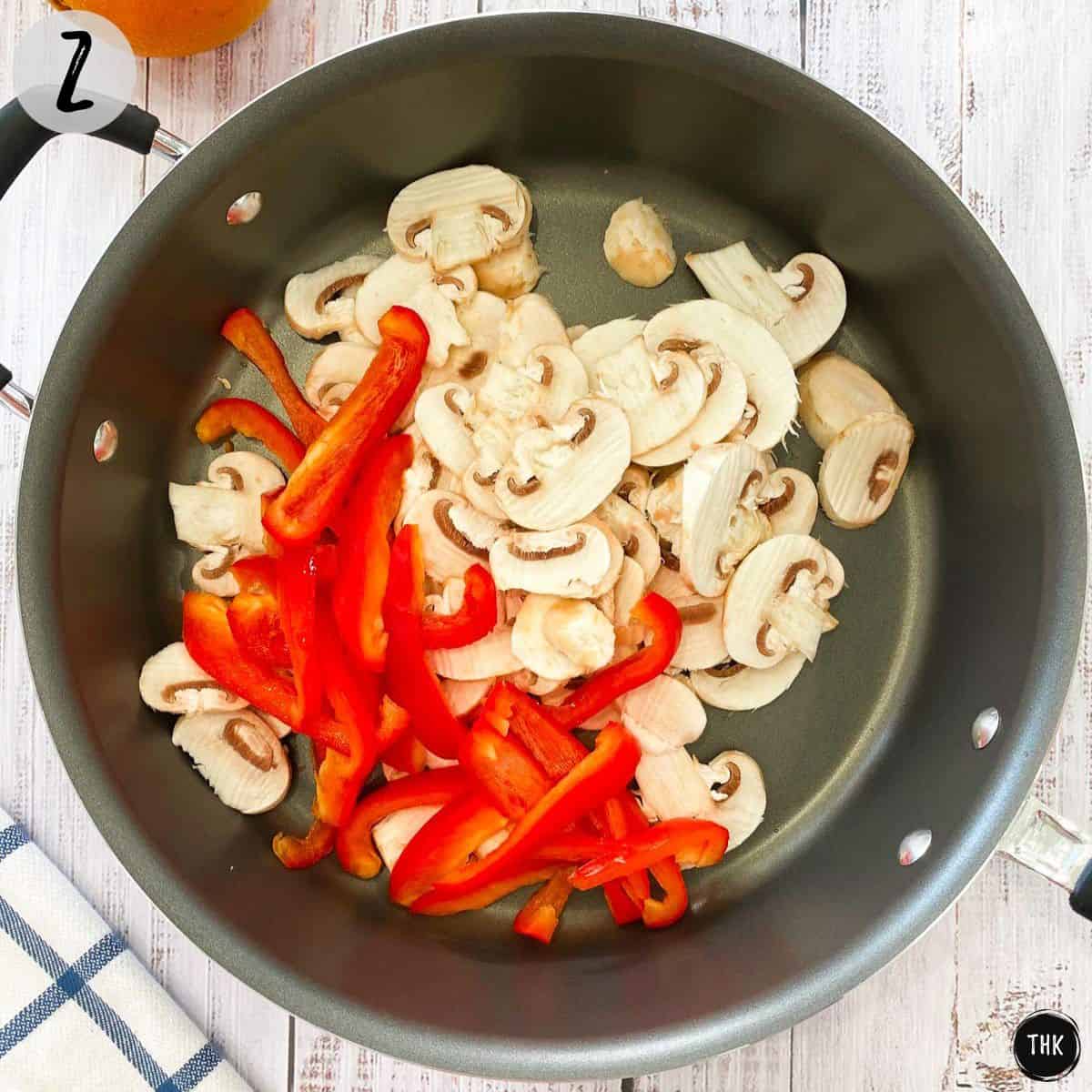 Sliced red peppers and mushrooms inside deep skillet.
