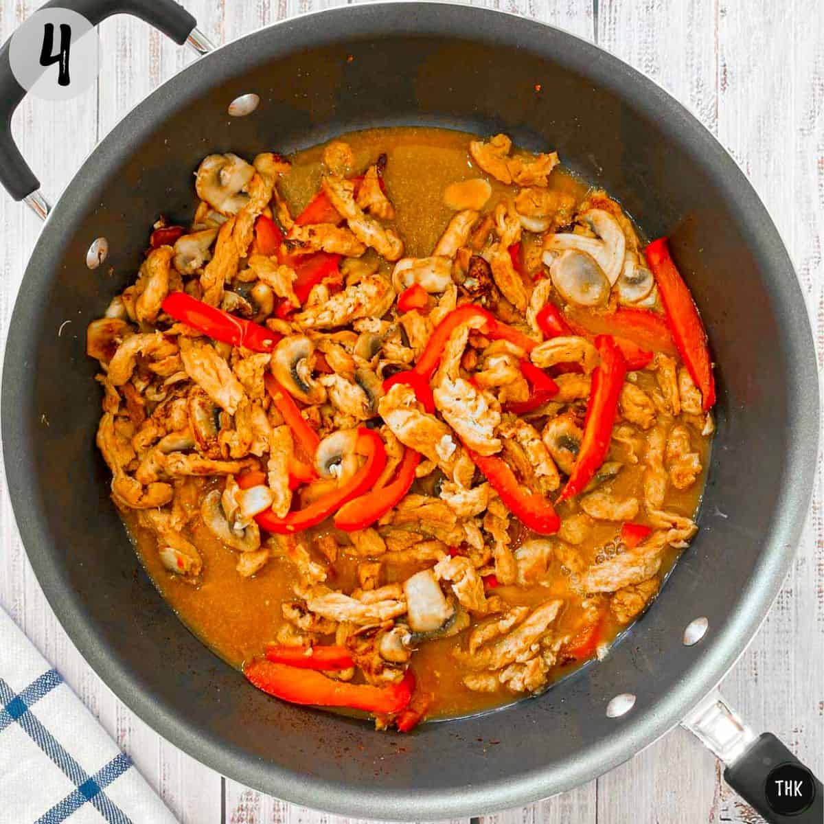 Soy curls, peppers, mushrooms and orange sauce inside deep pan.