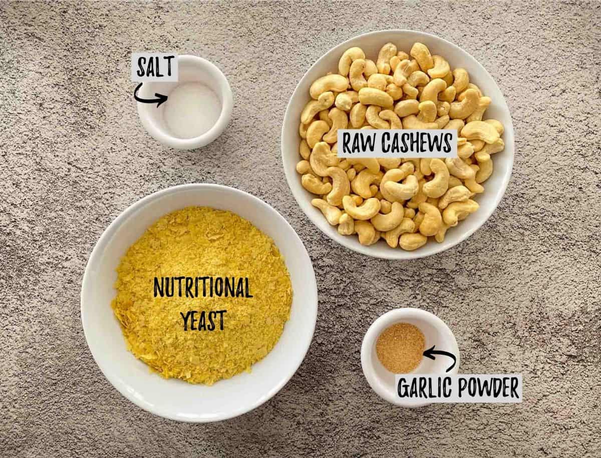 Bowl of cashews, nutritional yeast, salt and garlic powder on concrete deck.