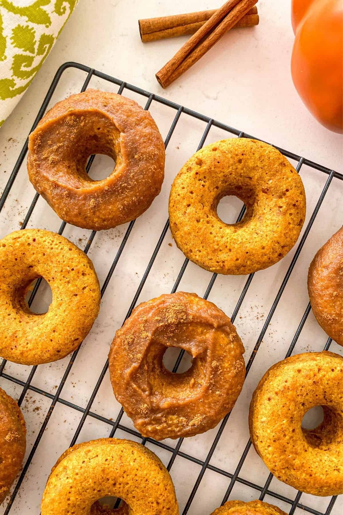 Pumpkin donuts on cooling rack with half plain and half glazed.