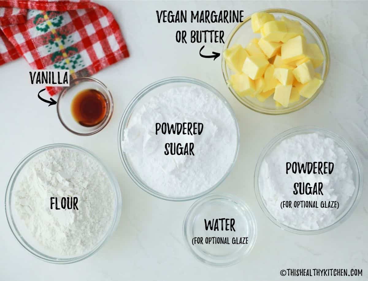 Glass bowls of flour, sugar, butter, water and vanilla on kitchen countertop. 