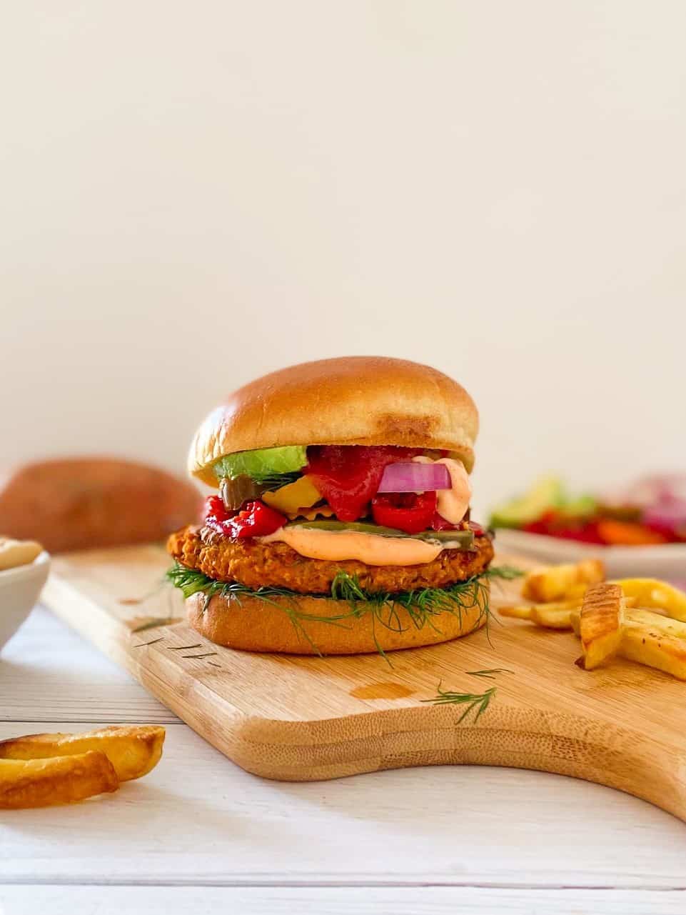 Burger in bun on cutting board with ketchup dripping down the front.