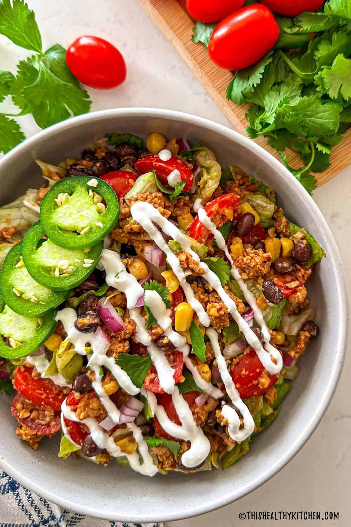 Vegan taco salad with veggies, black beans, and crema fresca on top.