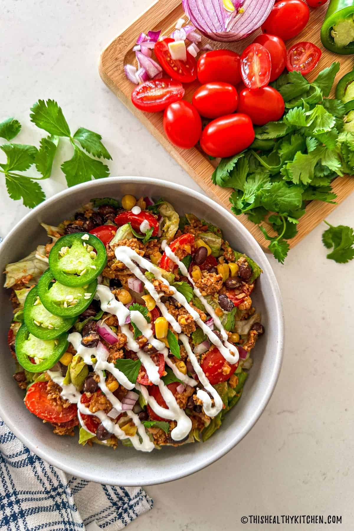 Vegan taco salad in bowl with cutting board of veggies on top above it.