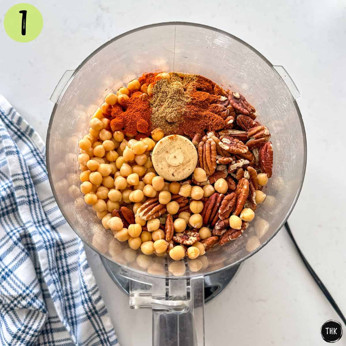 Food processor bowl with pecans, chickpeas, spices, and soy sauce inside.