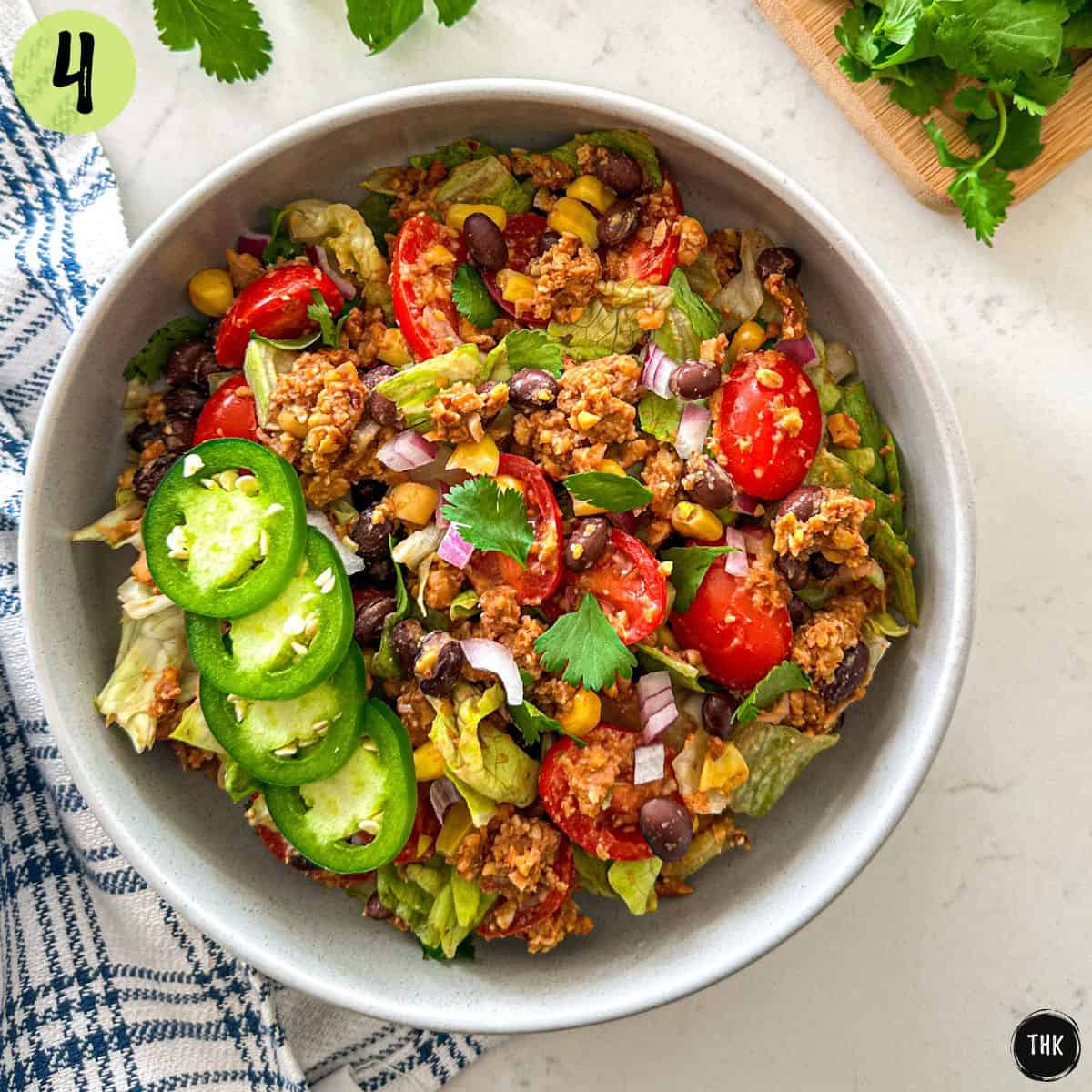 Vegan taco salad with veggies, black beans, and jalapenos on top.
