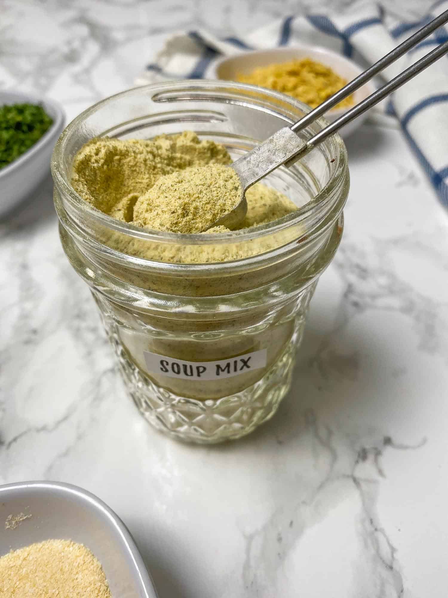 glass jar of bouillon powder with spoon ful of powder resting on top of the jar