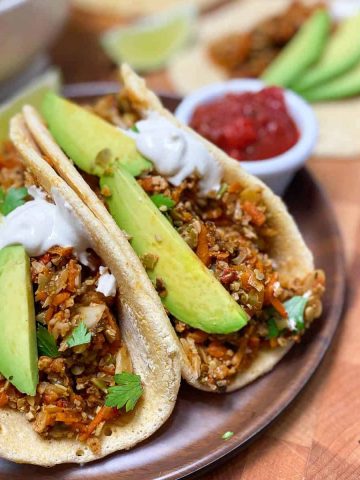 soft tacos on plate with avocado garnish and salsa for dipping