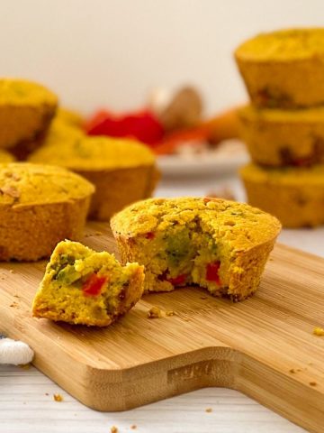vegan savoury muffin with triangular piece cut out on cutting board.