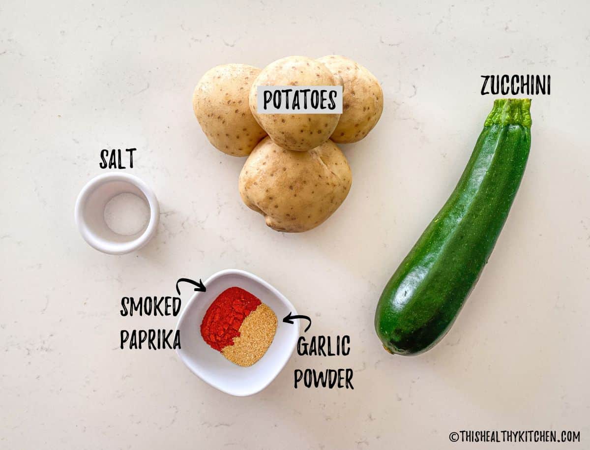 Potatoes, zucchini and spices on kitchen counter top.
